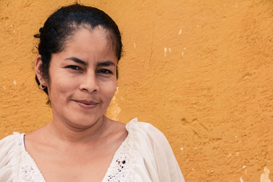 portrait of woman smiling at camera in front of adobe wall
