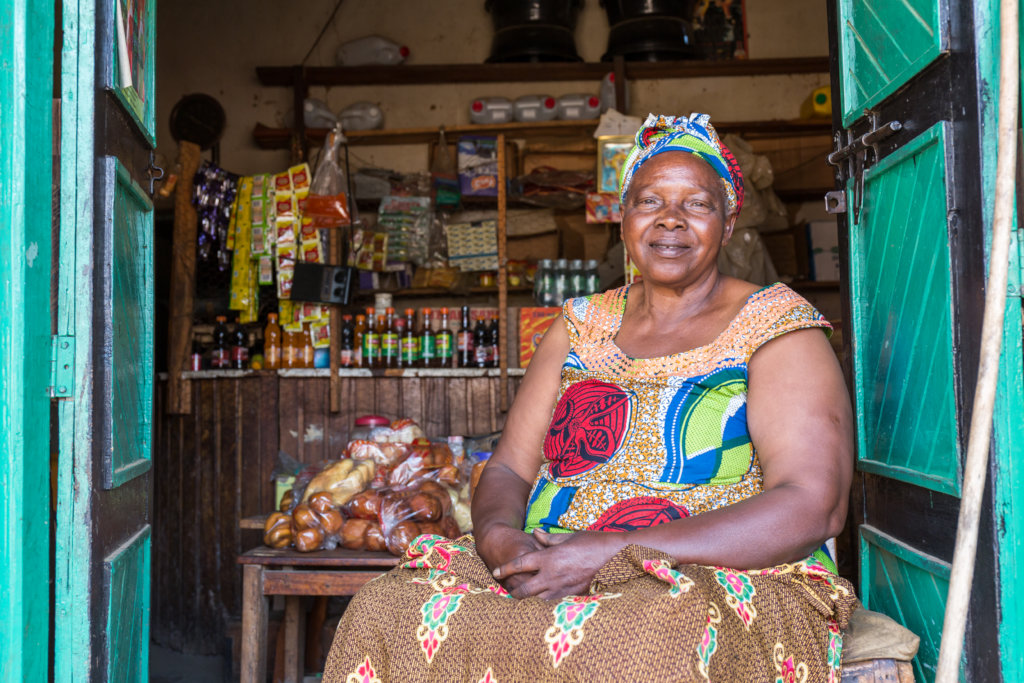 A smiling grandmother, sitting in front of her shop