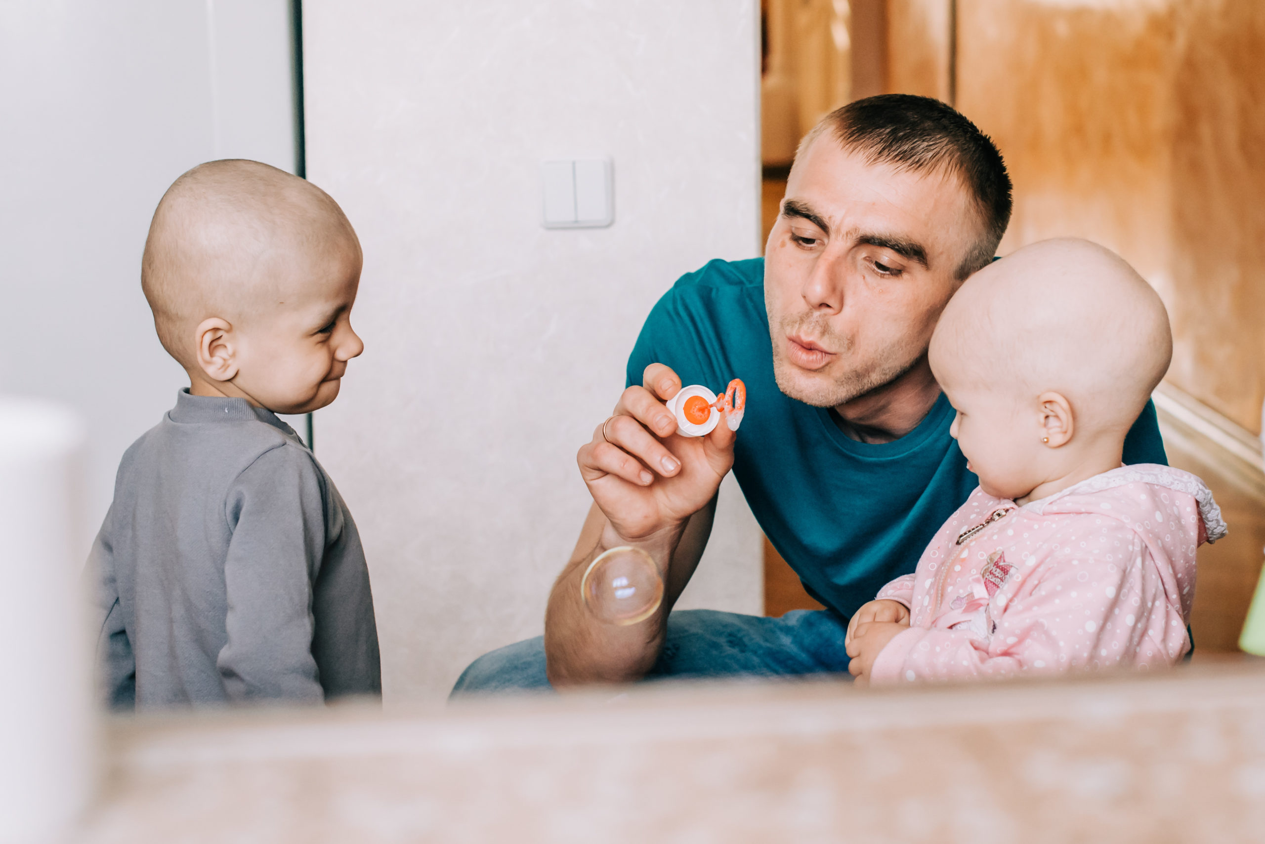A person blowing bubbles with two small children