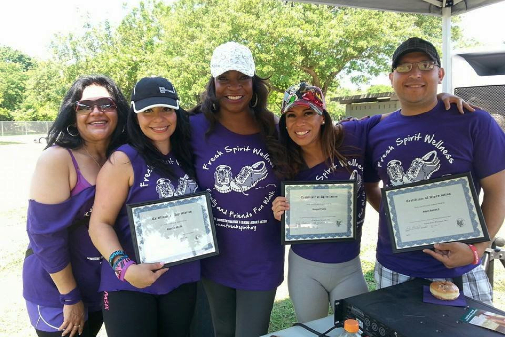 Women stand together holding up certificates of completion for an advocacy walk