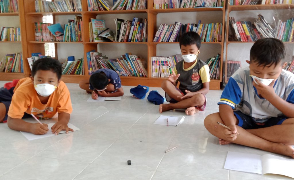 Students wearing masks doing school work in a small tutoring session in Indonesia