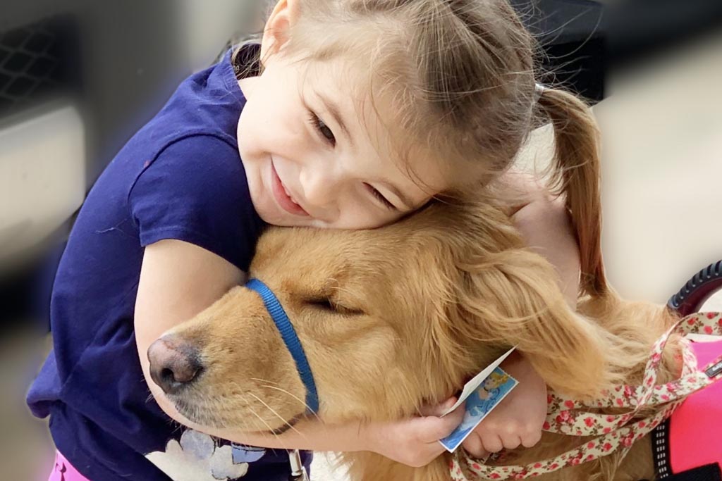 young girl hugs golden retriever