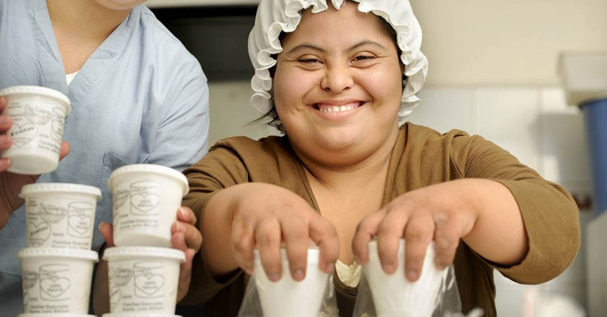 woman holding containers of fresh yogurt, as part of an innovative education program for kids with disabilities