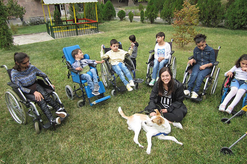 Children in wheelchairs surrounding therapy dog. Dogs with jobs help children with disabilities.
