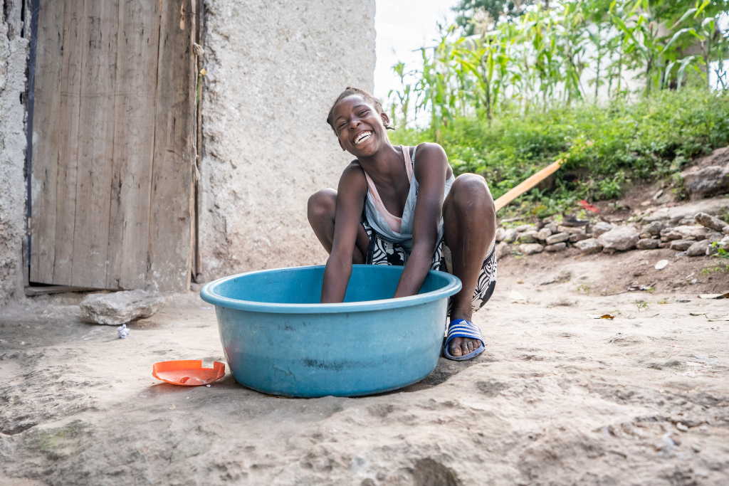 Woman smiles at the camera while washing something in a tub - photos of 2022