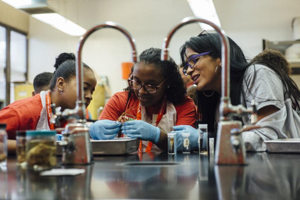 Three women gather around test tubes in a classroom - photos of 2022