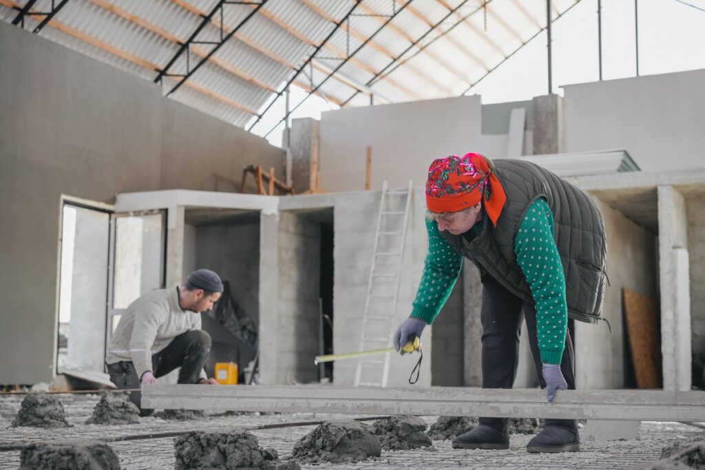 Two people work in a building with construction materials responding to crisis