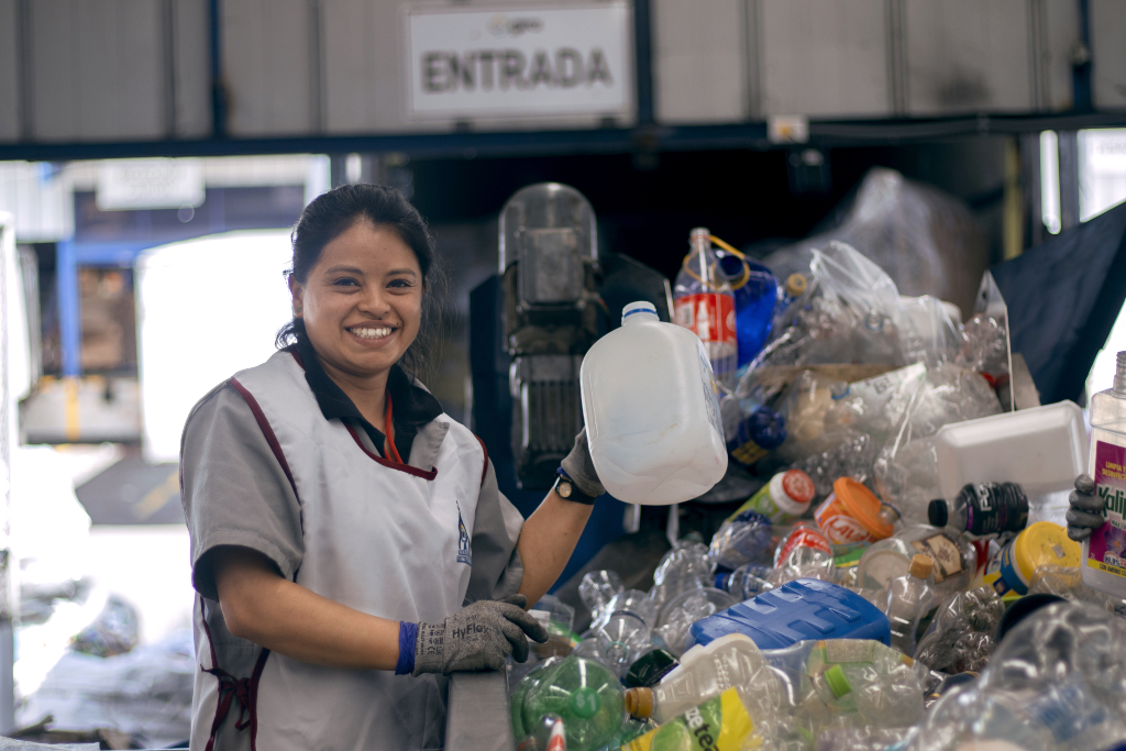 Woman working at recycling plant smiles at the camera