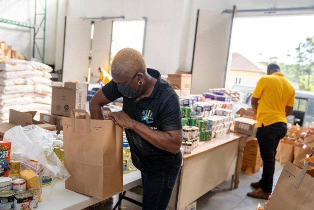 Two people pack food into bags for distribution