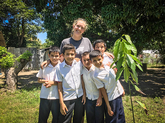 woman with five schoolchildren and a sapling