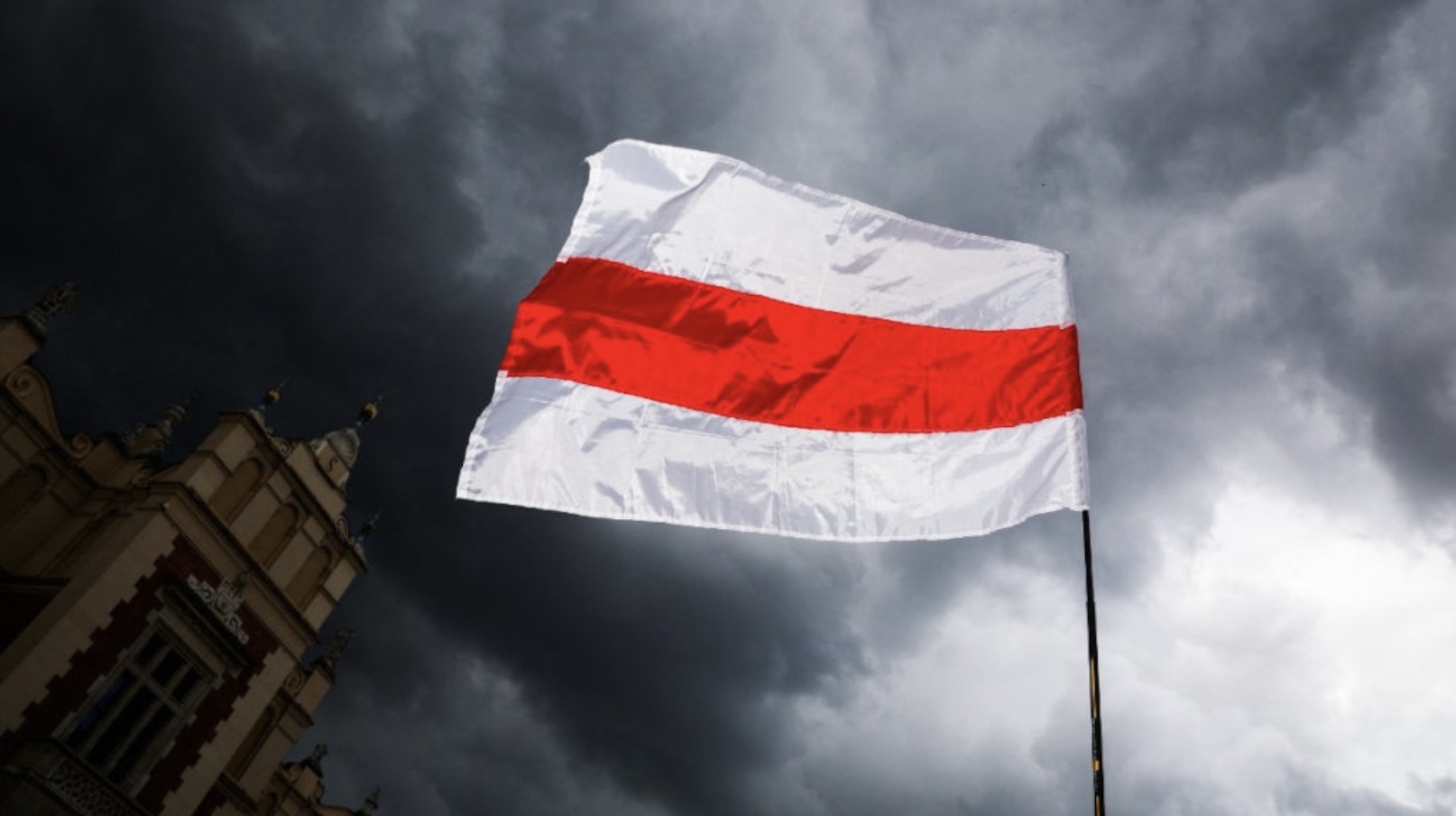 White flag with red stripe against clouds.