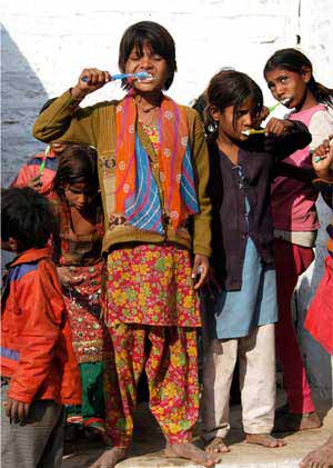 A group of children brushes their teeth