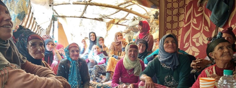 A photo of a group of 15-20 Moroccan women smiling at something in the distance
