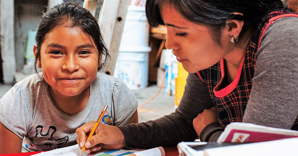student works with tutor, smiles at camera International Day of Education charities