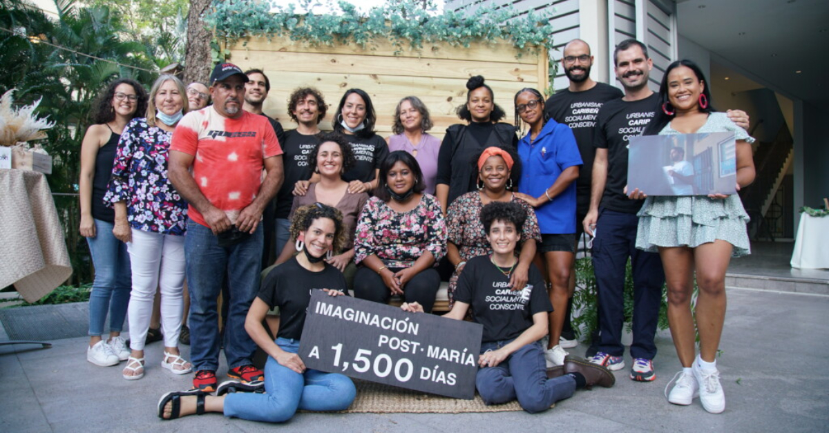 Group poses around a sign marking more than 1,500 days since hurricanes Maria and Irma.