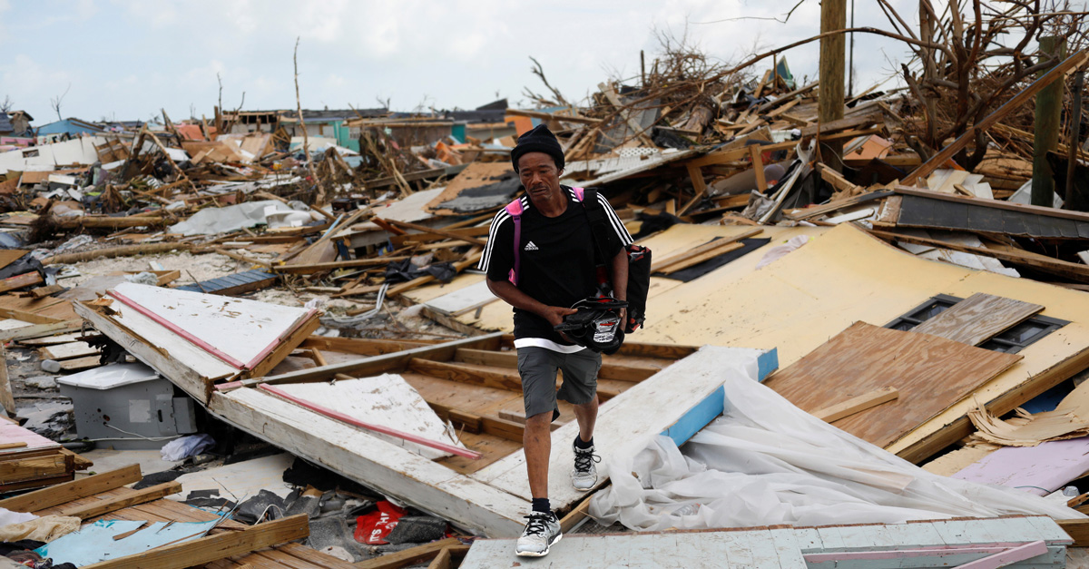 Man walking through the rubble left behind by Hurricane Dorian