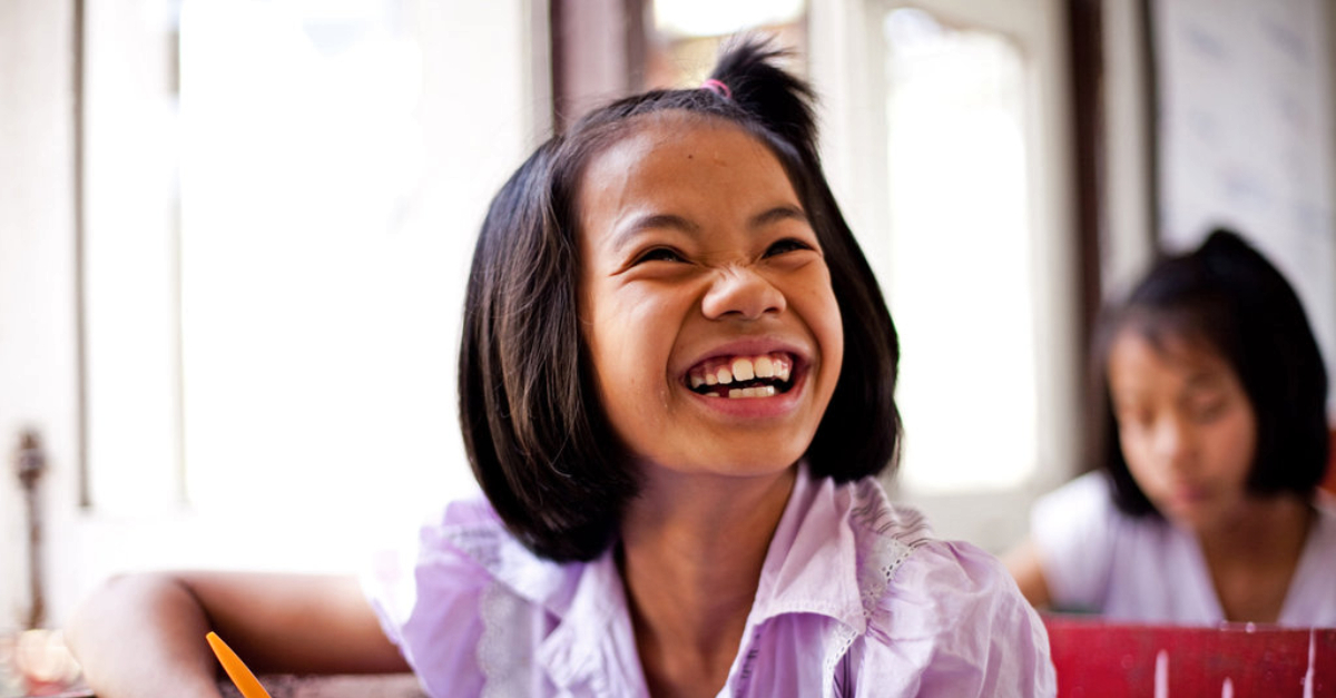 girl sitting at desk laughs at the camera representing successful #givingtuesday campaigns