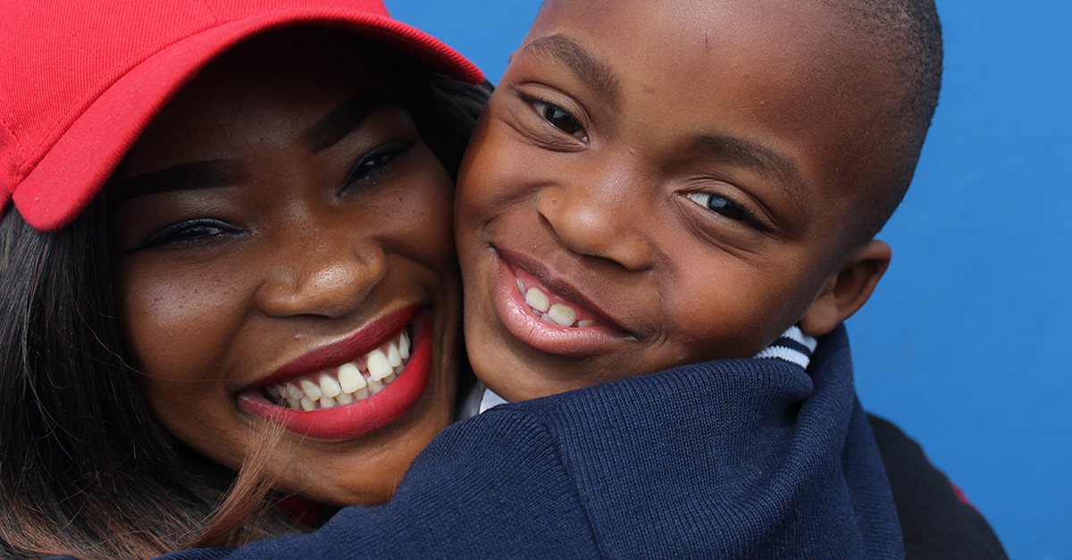 creative Valentine's gift. A woman in a red hat holds embraces a young boy.