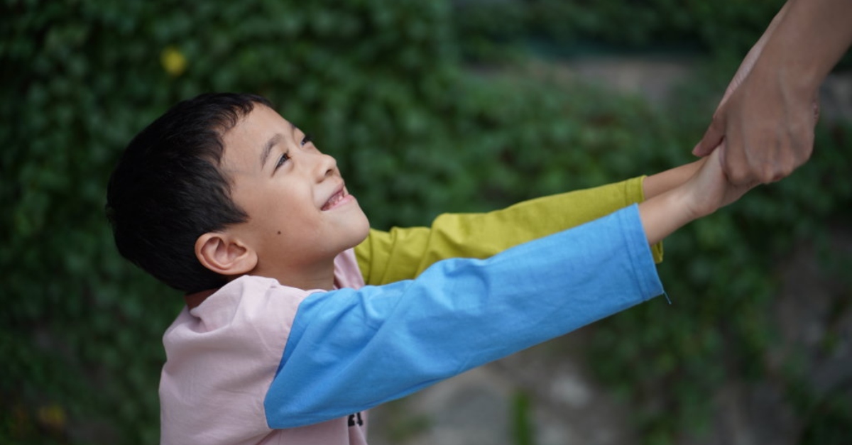 Young boy smiling and reaching out for someone's hand | Microgrants COVID-19