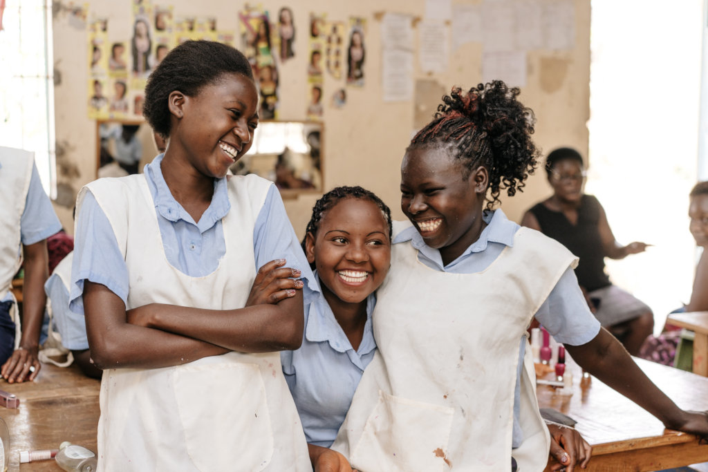 Three girls smiling together in a classroom