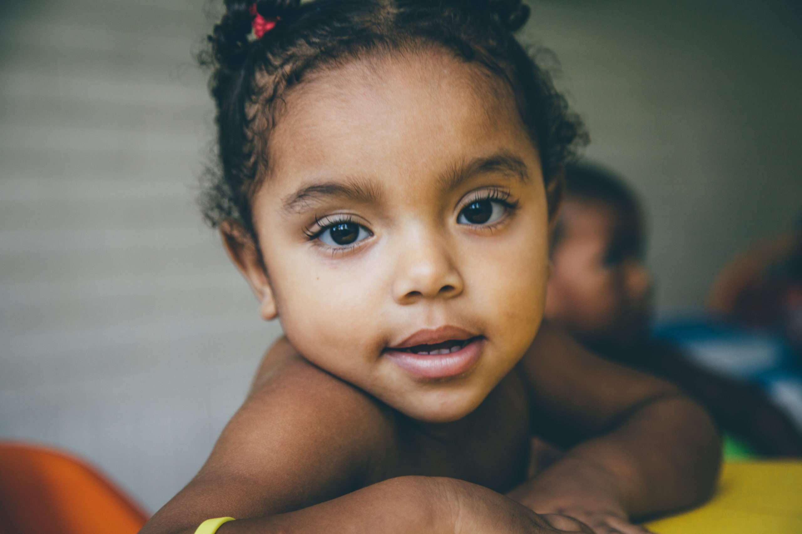 A baby in a high-chair, smiling at the camera. Amazing nonprofit photos