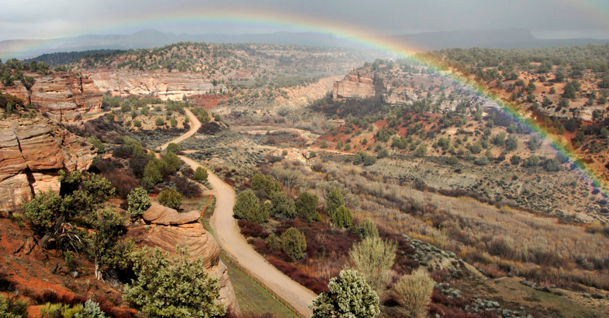 Company ethics. A rainbow stretches over a canyon landscape.