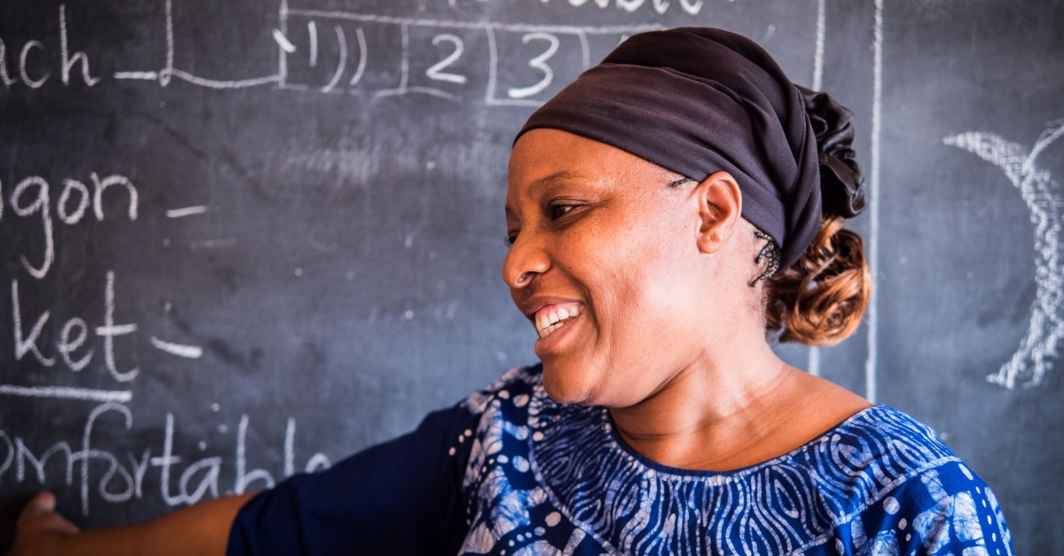 A woman smiling in front of a chalkboard