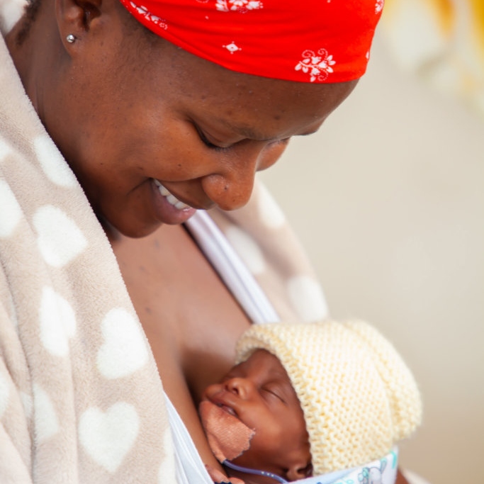 A mother in a red bandana holds her newborn baby