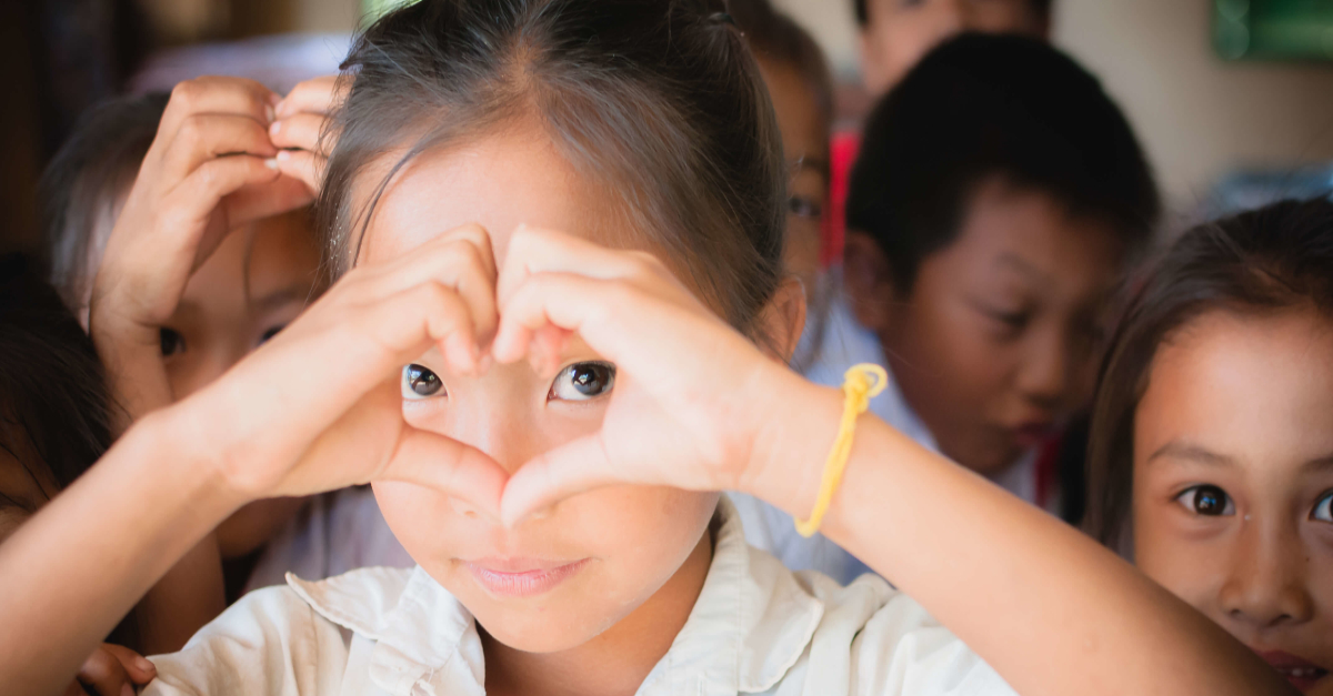 Girl making a heart with her hands. Virtual gift idea for the 2020 holiday season.