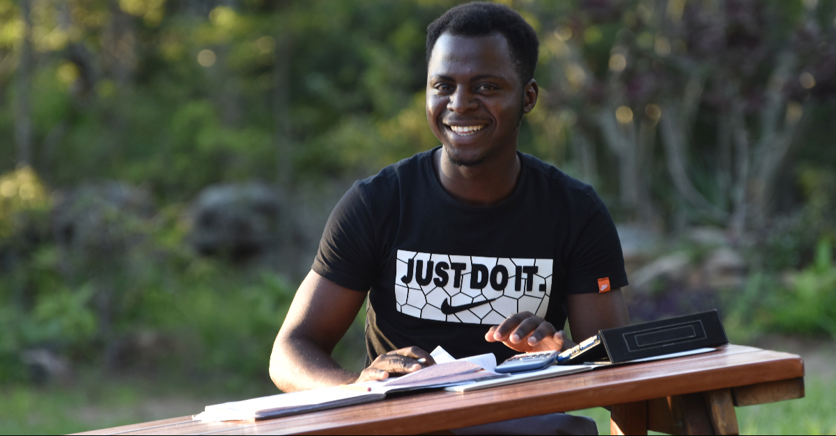 Sustainable fundraising strategy. A man in a black T-shirt sits at a picnic table with notebooks and a calculator in front of him