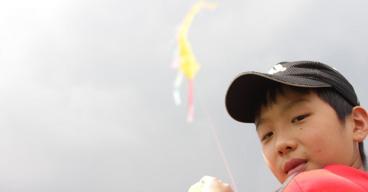 A boy in a black hat holds a yellow kite above his shoulder. iapan-earthquake-tsunami-recovery