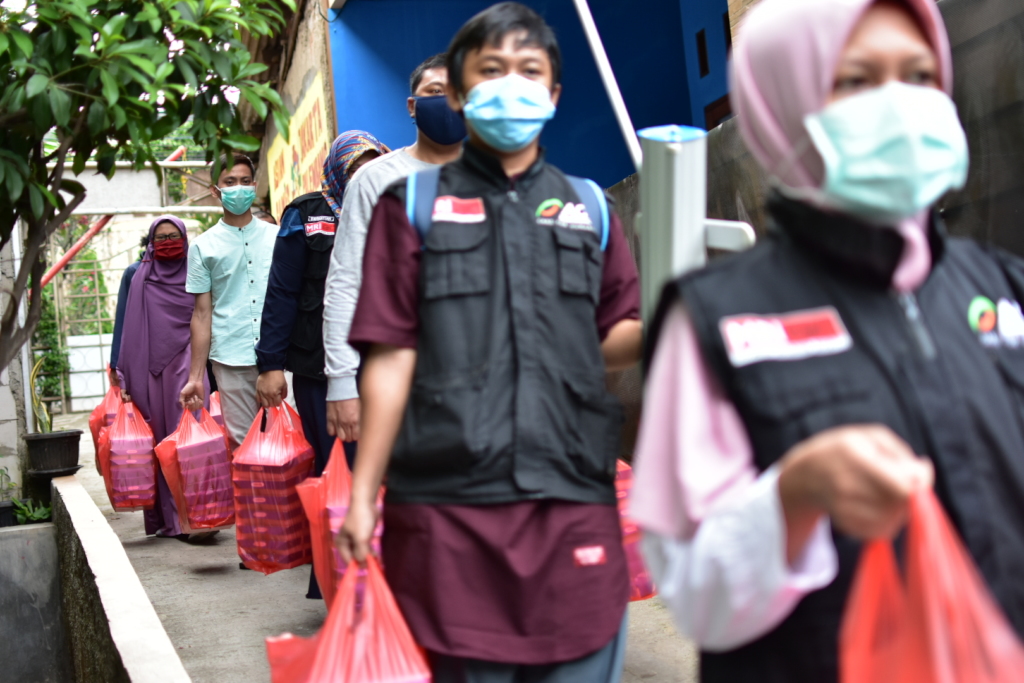 Workers hold red plastics bags with food packages inside