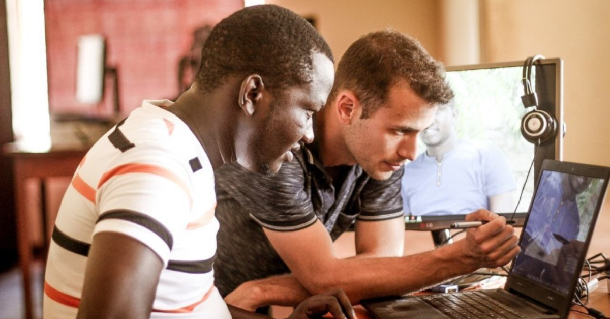 Two men look at a laptop screen