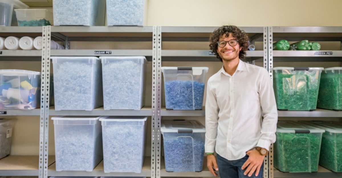 A man in a white shirt stands in front of bins of colored plastic pieces