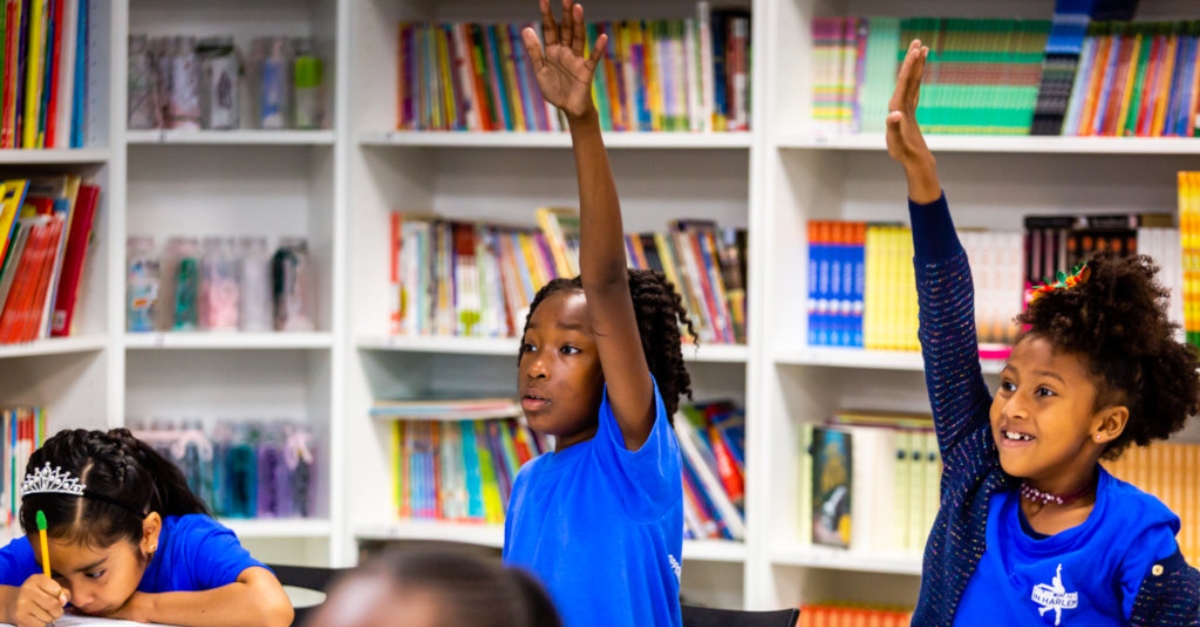 business leaders social change. Girls in blue uniforms eagerly raise their hands in a classroom