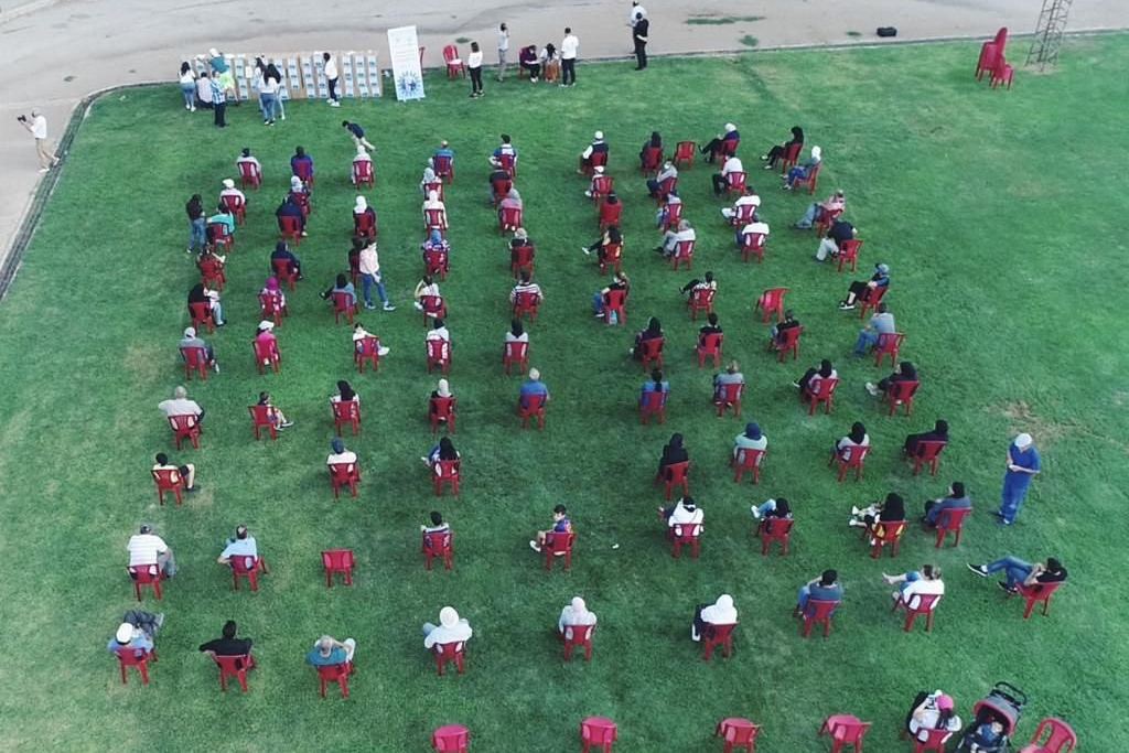 Aerial view of a socially distanced training with rows of attendees seated in red chairs