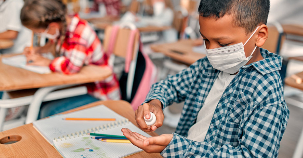 A student using hand sanitizer at their desk