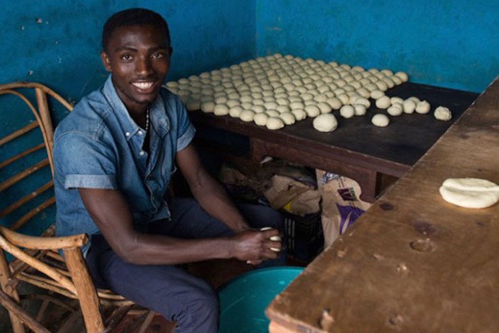 A man sits in front of a table covered with rolled dough