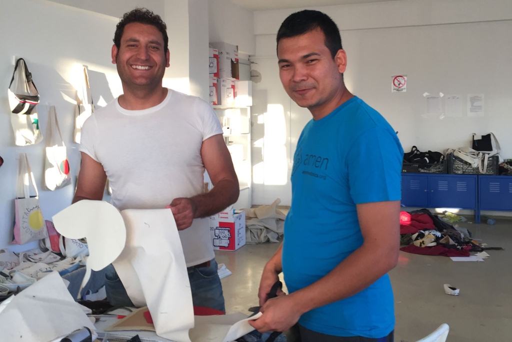 Two men in t-shirts stand at a table holding art supplies