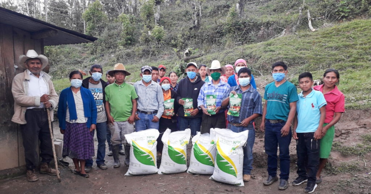 Around 20 people standing in front of new bags of soil and farming materials in Honduras