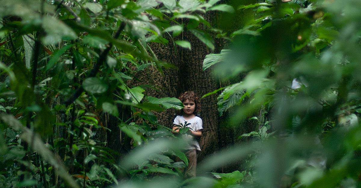 girl looking through tree foliage