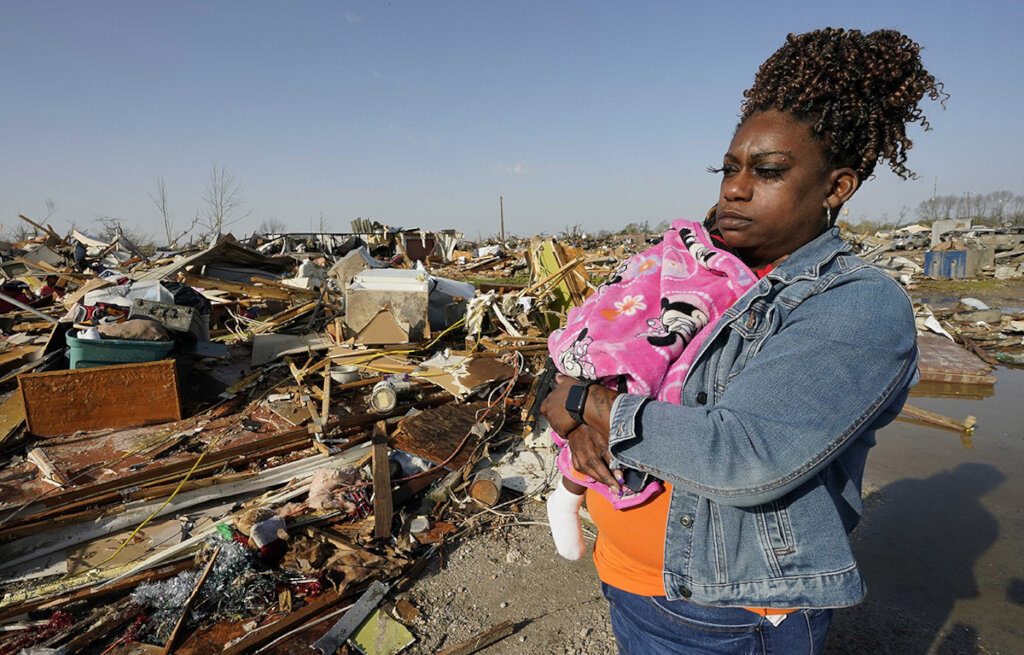 A woman holds her child among destroyed buildings and debris.