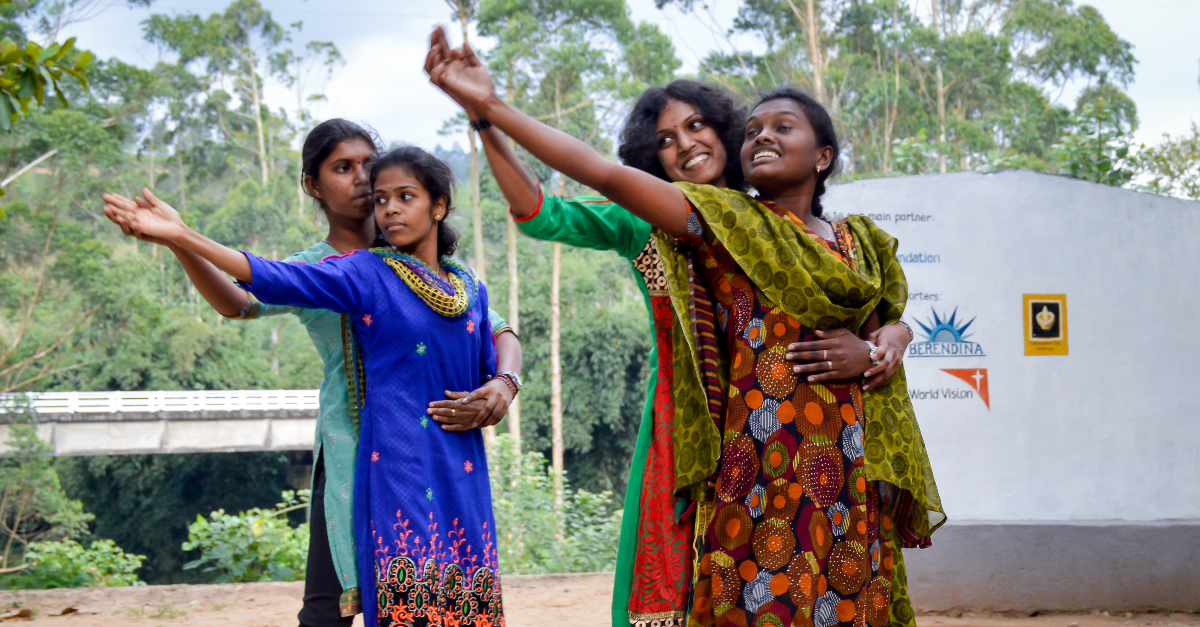 Two pairs of women learn how to dance and hold their hands out