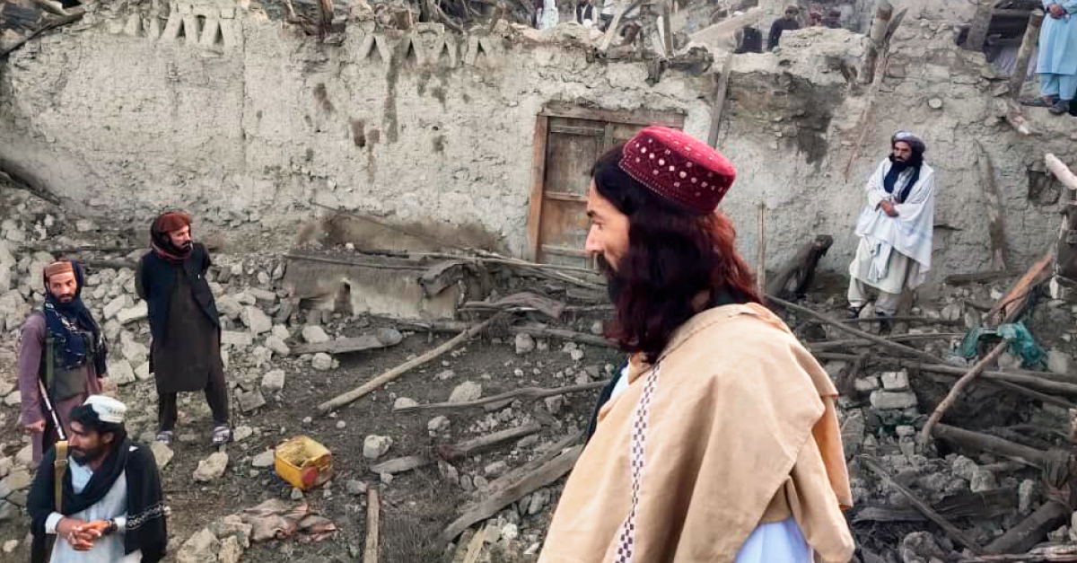 A man in tan clothing looks at buildings crumbled by the earthquake in Afghanistan