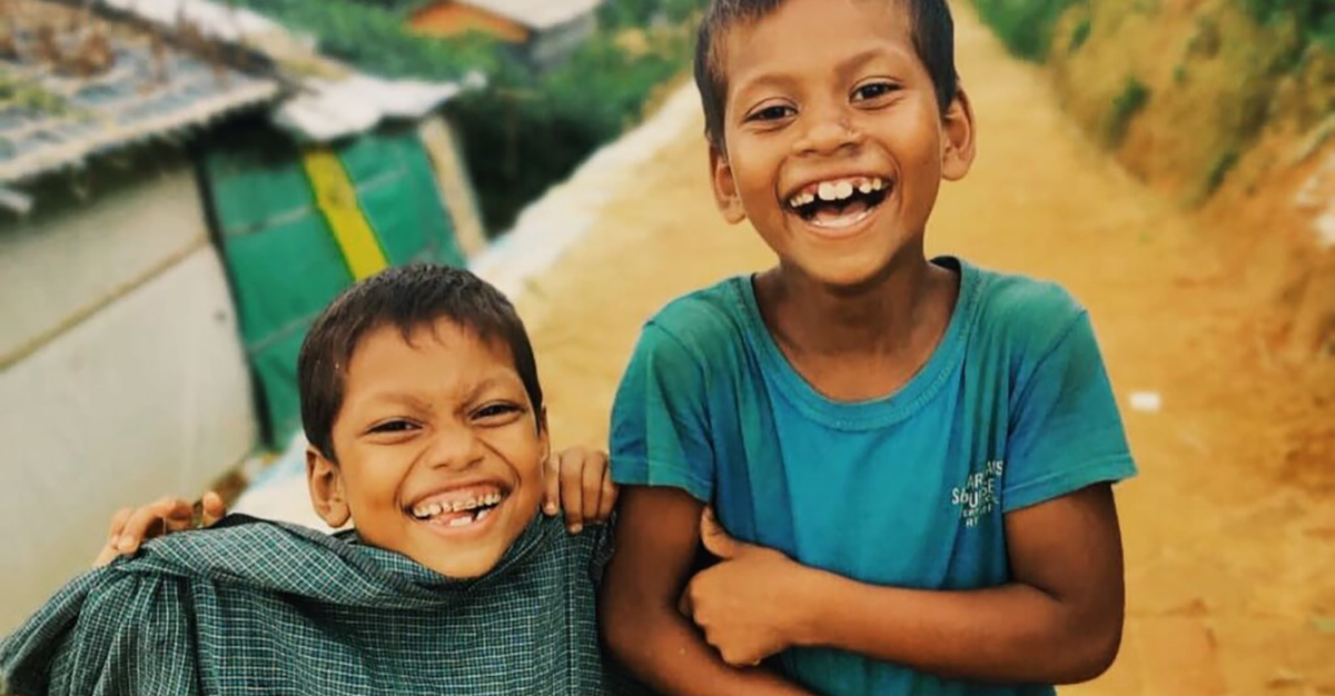 How to help Rohingya refugees featured photo features two little boys on a dirt road.