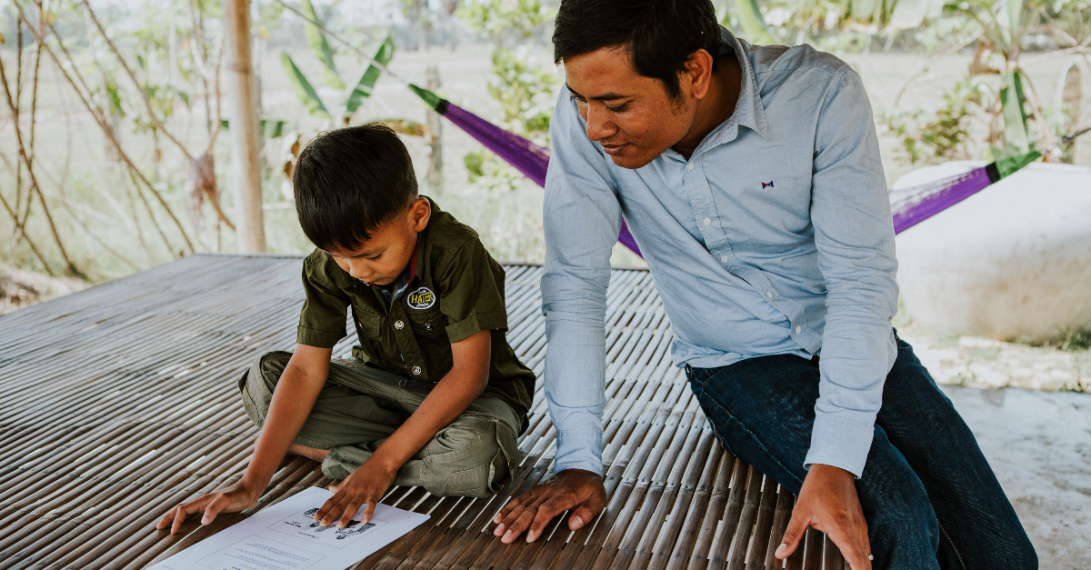 Child and adult sit together looking at a sheet of paper. Corporate disaster response decisions