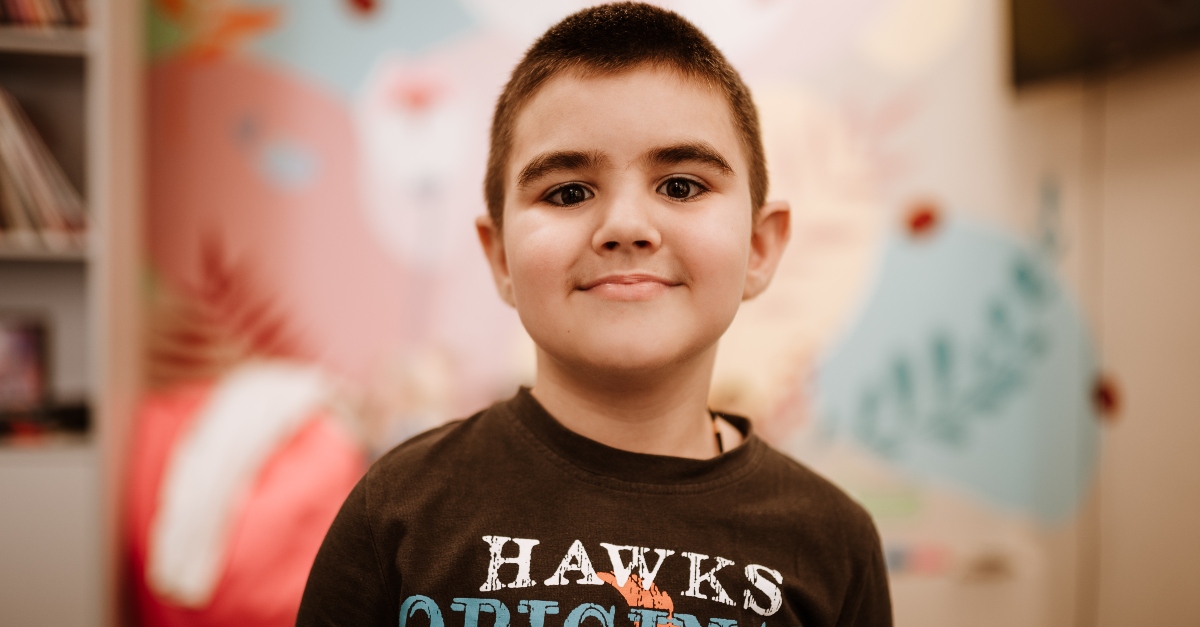 A young child stands in front of a blurry pastel background with flowers. The text, "Here's what you + the GlobalGiving community achieved in 2022" is overlaid on the image.