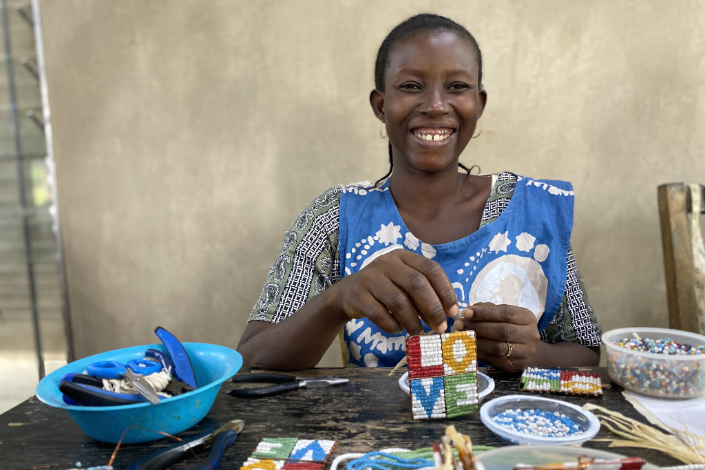 Woman holds up her artisan craft, smiling at the camera