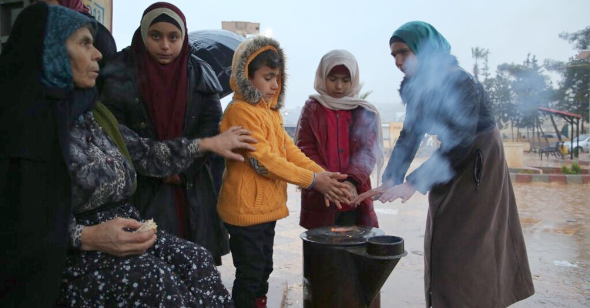 People of all ages gather around a fire. turkey and syria earthquake