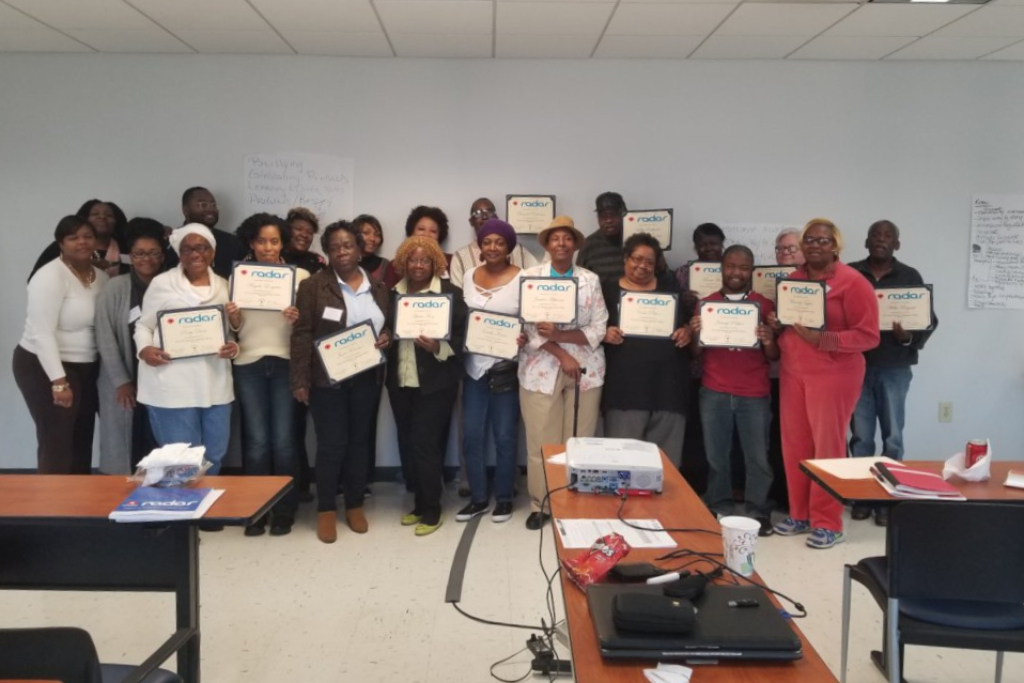 A group of mothers stands together holding certificates